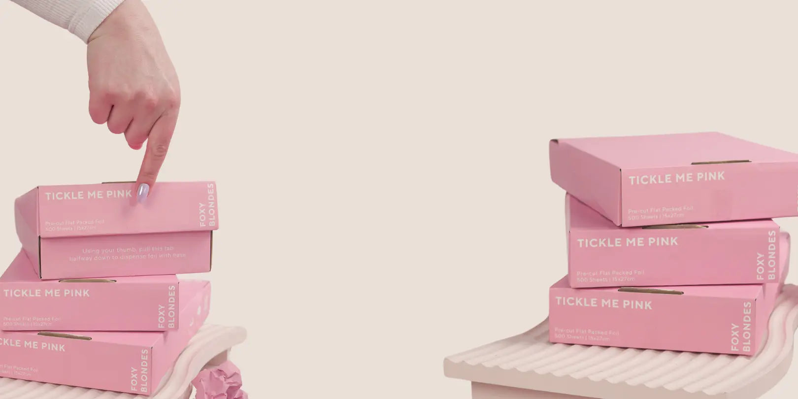 Two stacks of Foxy Blondes 'Tickle Me Pink' pre-cut flat-pack hair foil boxes (500 sheets, 15x27cm), displayed on pink ridged stands with crumpled foils.
